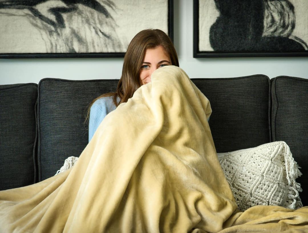 Woman curling up in a blanket.